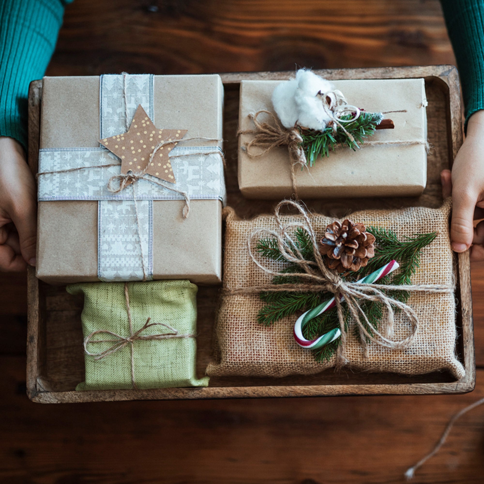 woman holding presents wrapped in rustic style, zero waste, plastic free, sustainable wrapper.