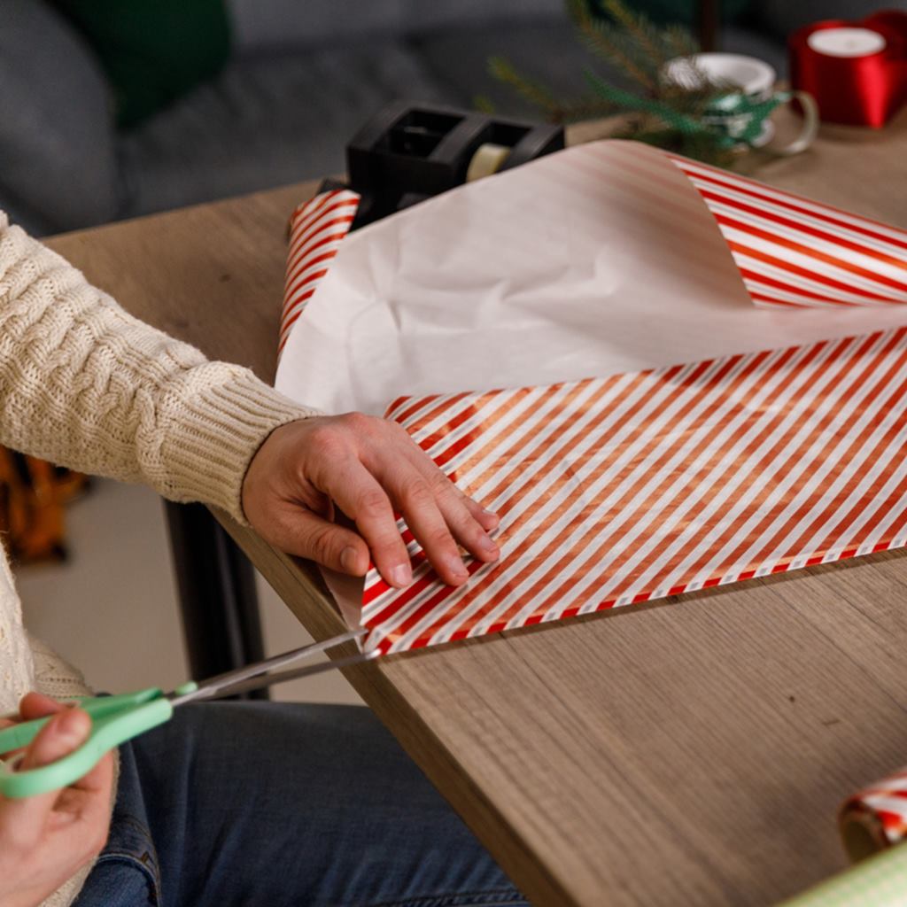 man cutting a gift wrapping paper with a scissor