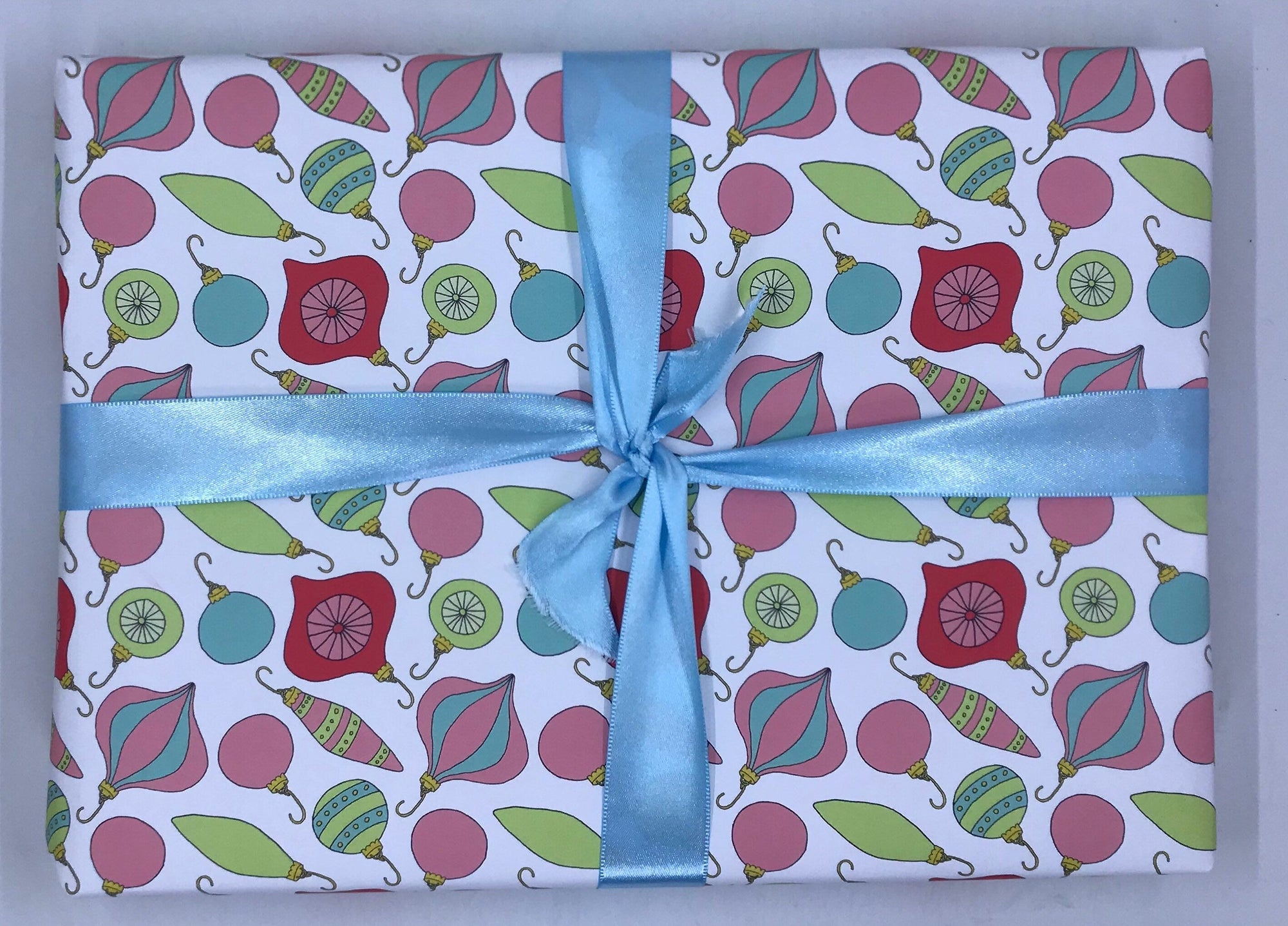 Whoville Style Christmas Ornaments diagonally printed on a white sheet of wrapping paper with a baby blue ribbon tied around it